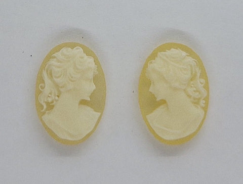 A pair of beige and white colored resin cameos shaped like a girl's profile.
