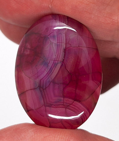 Close-up of a pinkish-red gemstone held between fingers